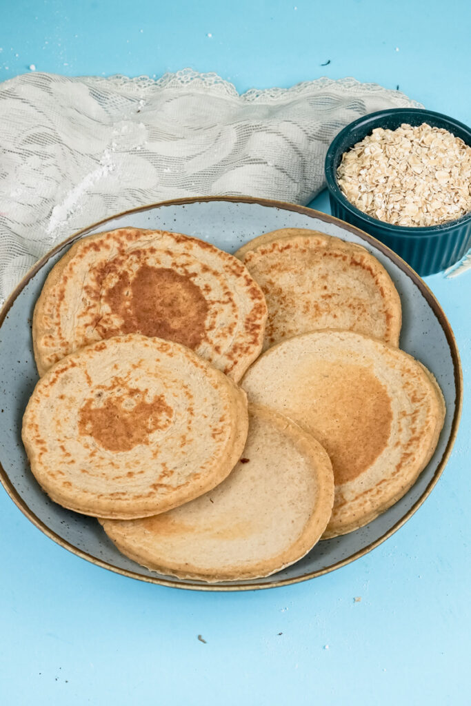 Homemade oat pancakes on plate with rolled oats bowl