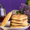 Golden gluten-free pancakes stacked on plate with purple background