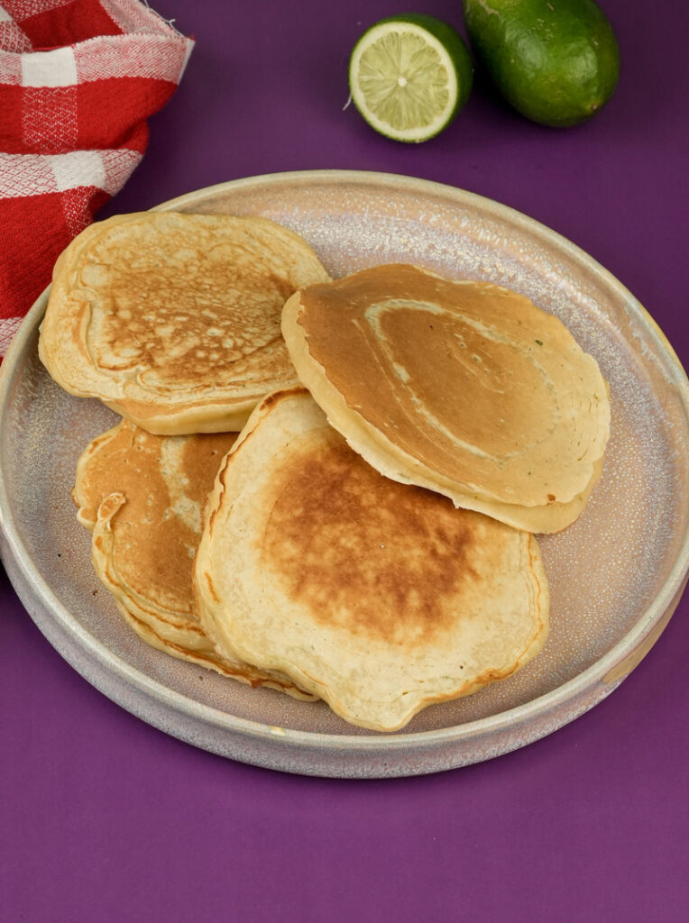 Golden lemon ricotta pancakes on plate with fresh lime garnish