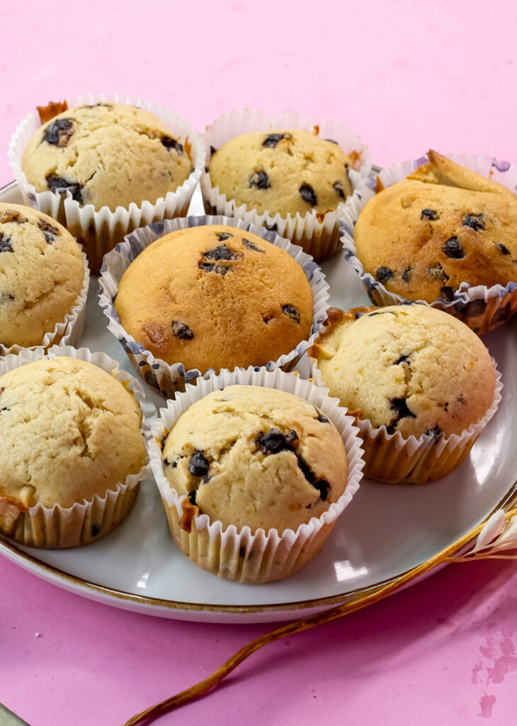 Golden mini chocolate chip muffins on elegant white serving plate