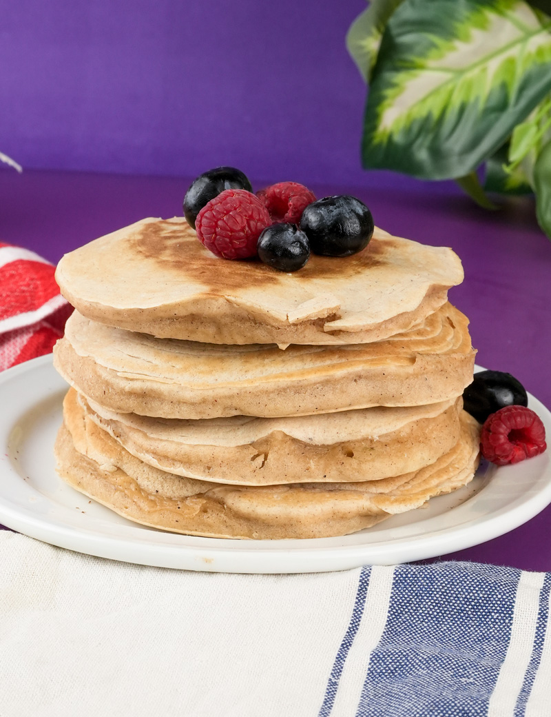 Golden silver dollar pancakes garnished with mixed berries on white plate