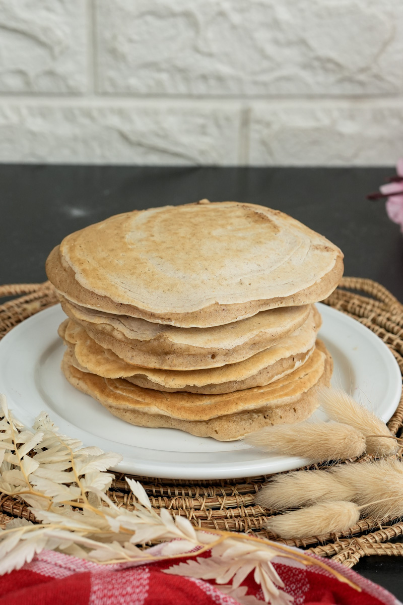 Stack of golden whole wheat pancakes on white plate
