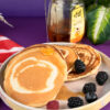 Honey being drizzled on silver dollar pancakes with wooden dipper