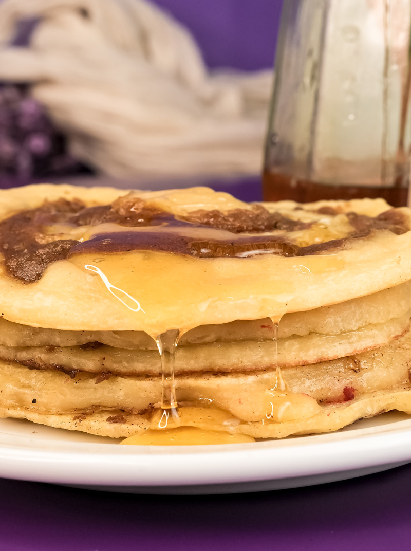 Honey cascading down sides of stacked cinnamon roll pancakes