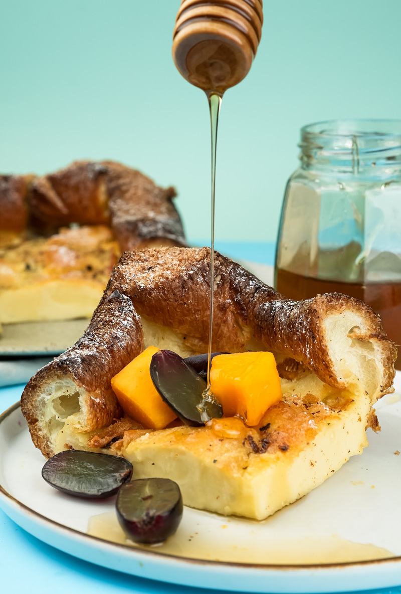 Honey drizzled over German pancake slice with fresh fruit