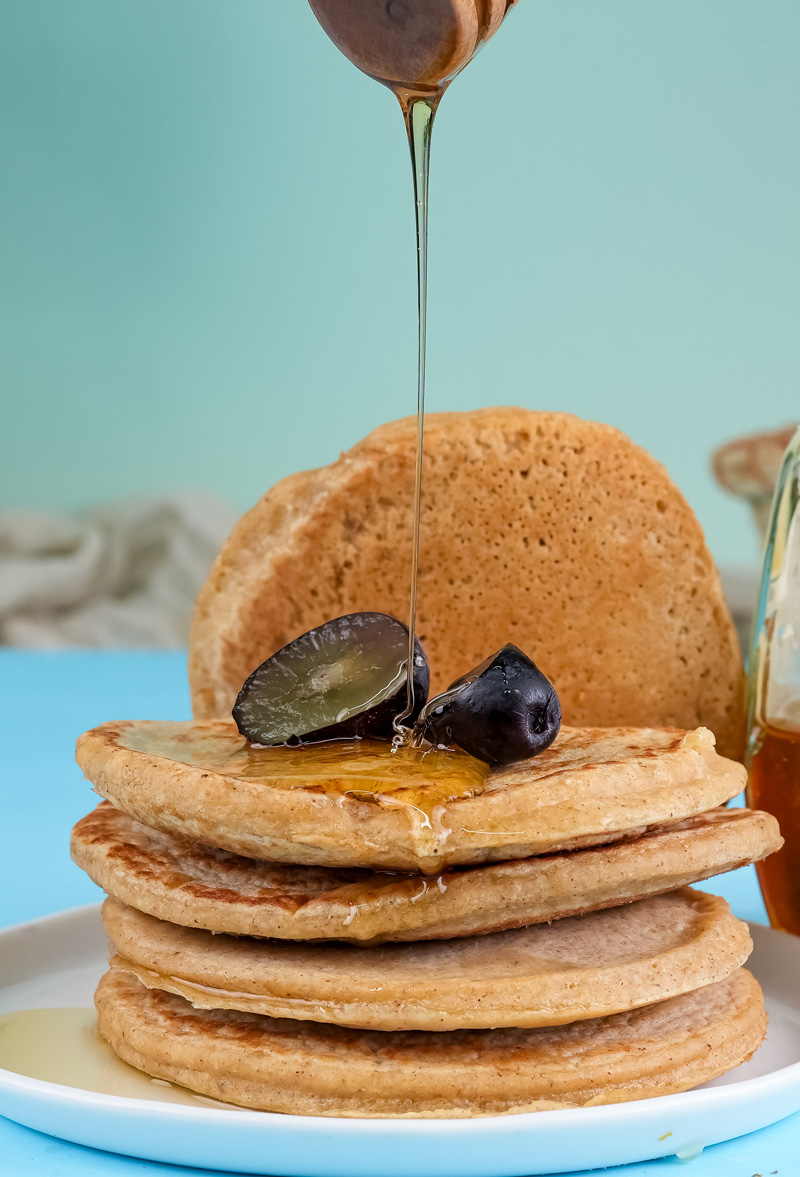 Honey drizzling over stacked oat pancakes with dates