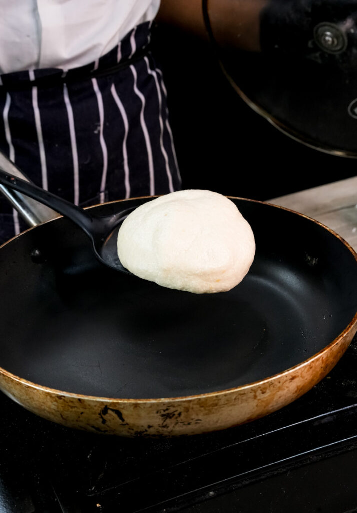 Japanese pancake cooking in pan on stovetop