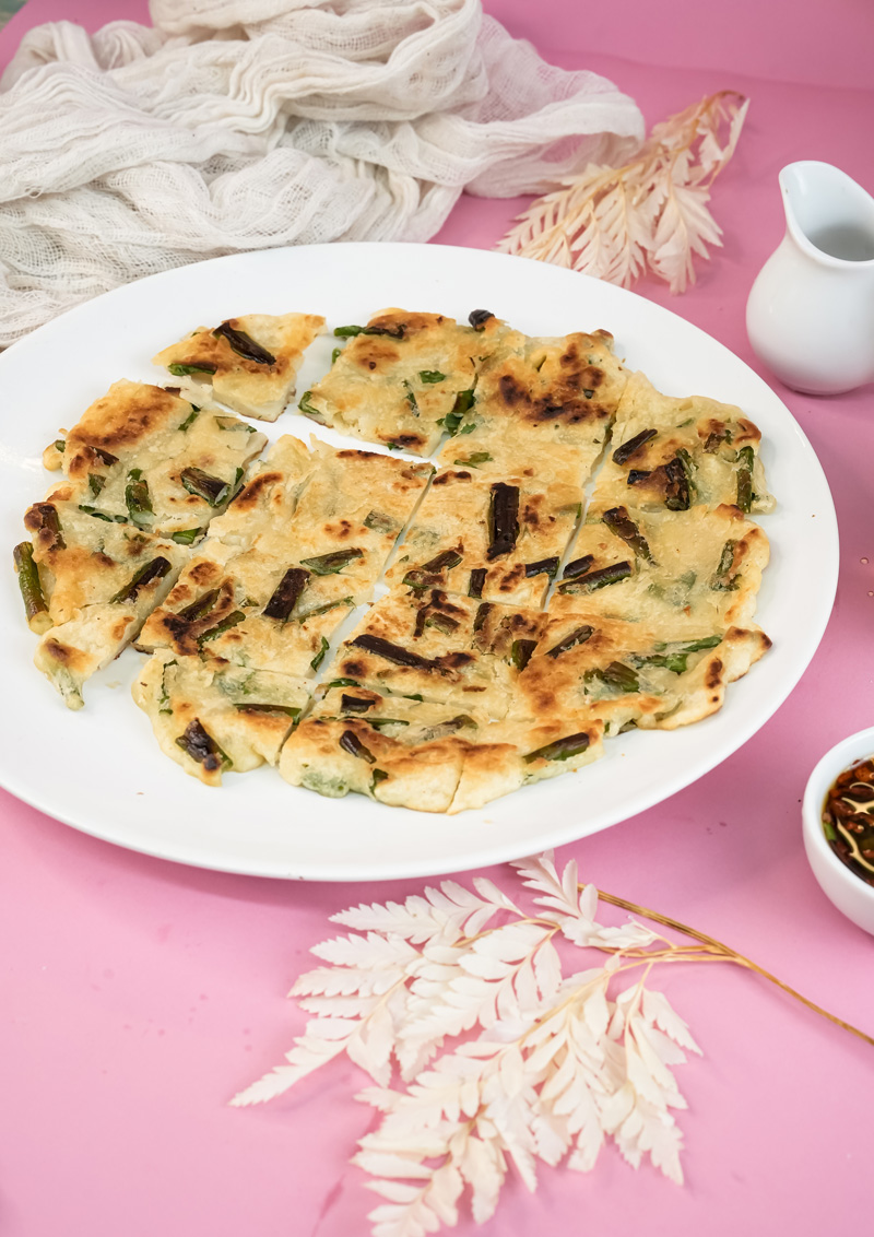 Plated Korean pajeon cut into squares with chopsticks