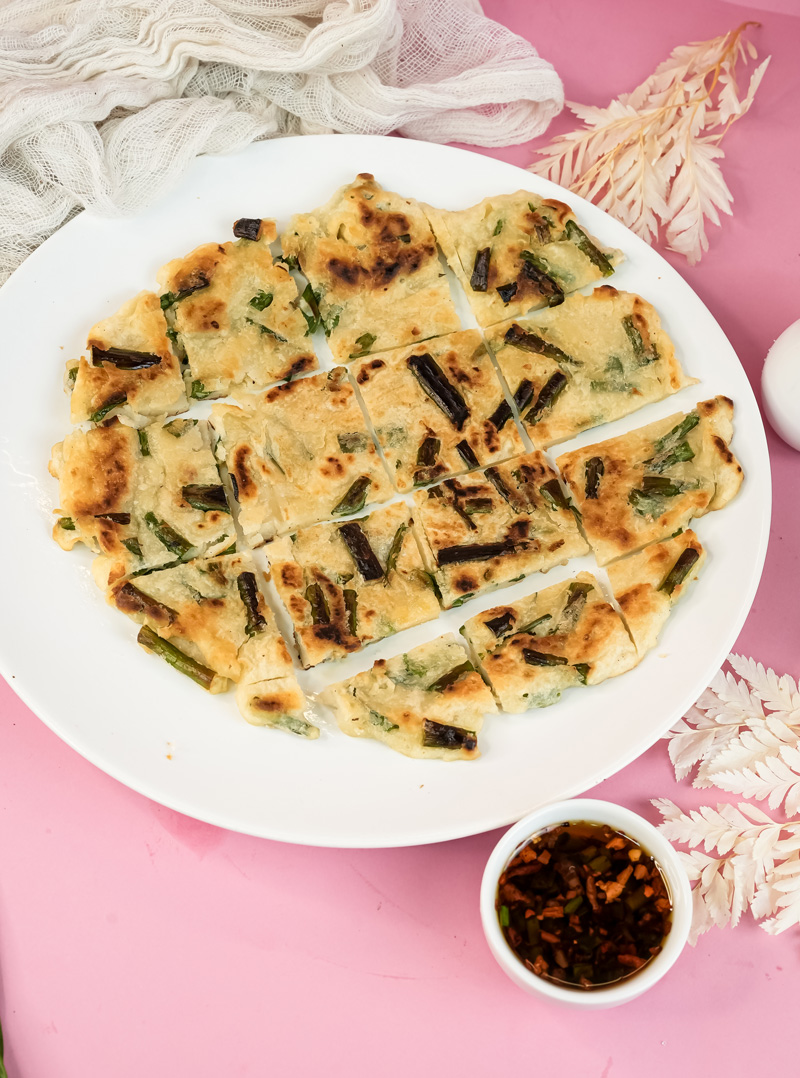 Cut Korean pancake arranged on white plate with sauce