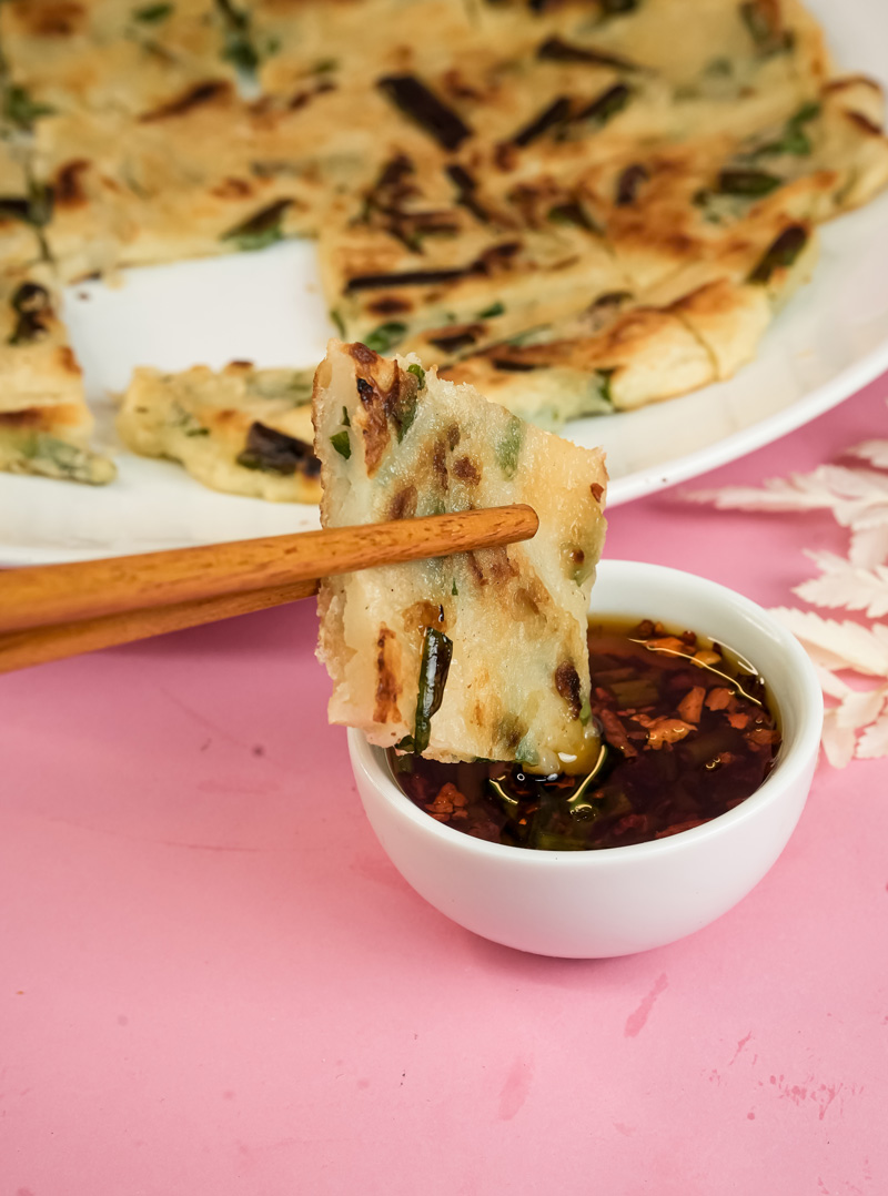 Picking up Korean pancake piece with chopsticks for dipping