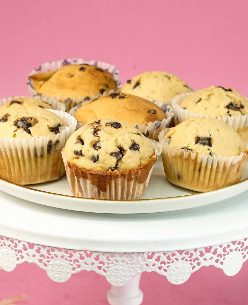 Mini chocolate chip muffins on white cake stand with pink background