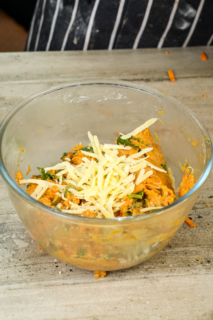 Mixing shredded mozzarella cheese into pizza muffin batter