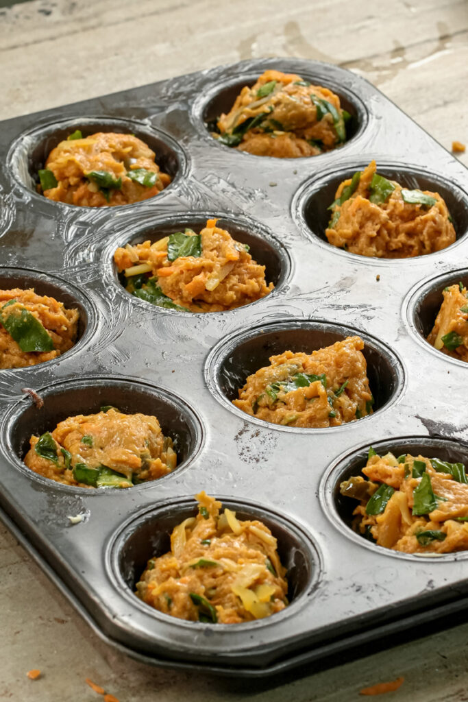 Muffin tin filled with unbaked pizza muffin mixture