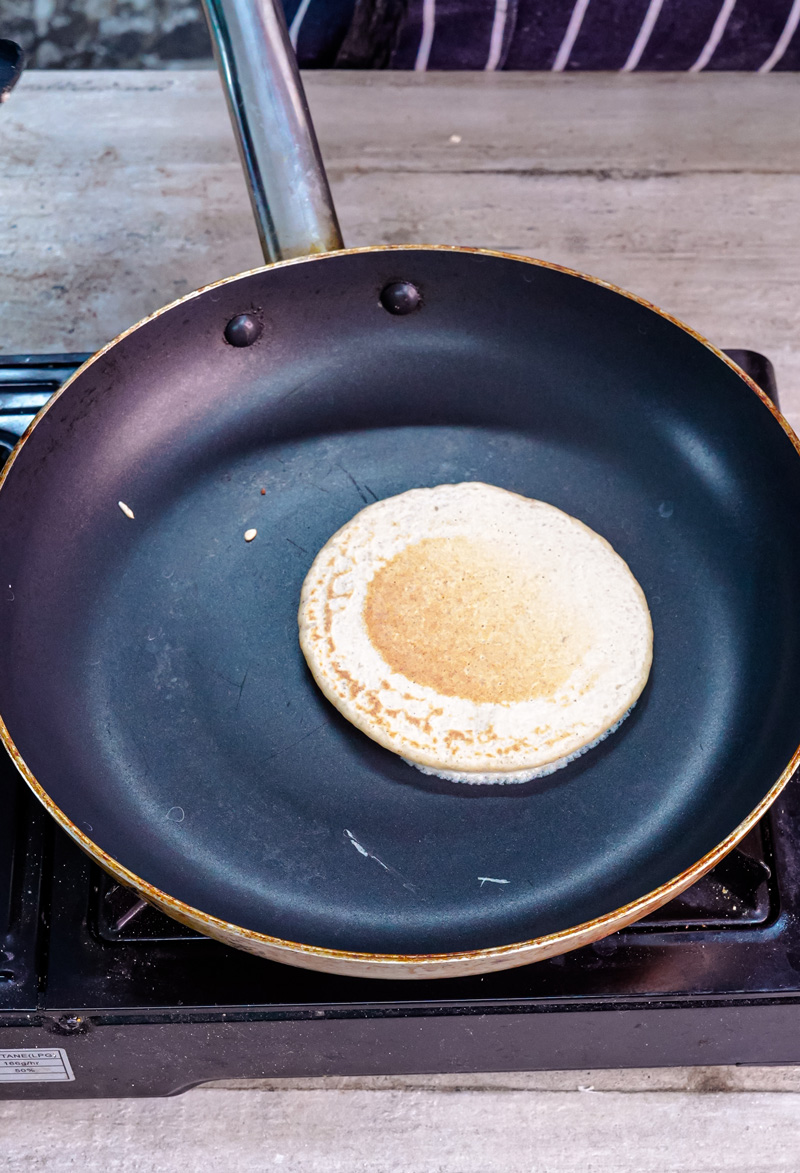 Oat pancake cooking in skillet showing texture