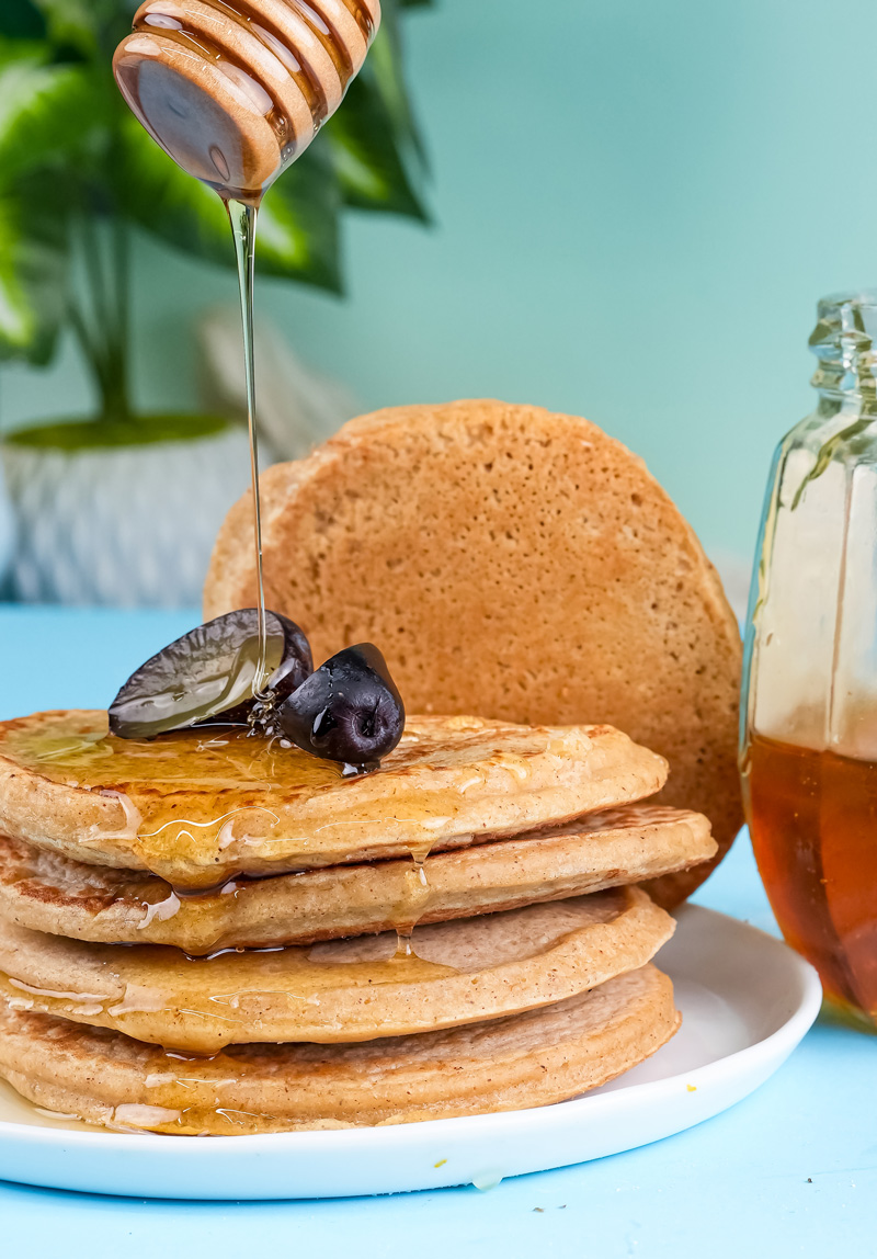 Honey being drizzled over homemade oat pancakes