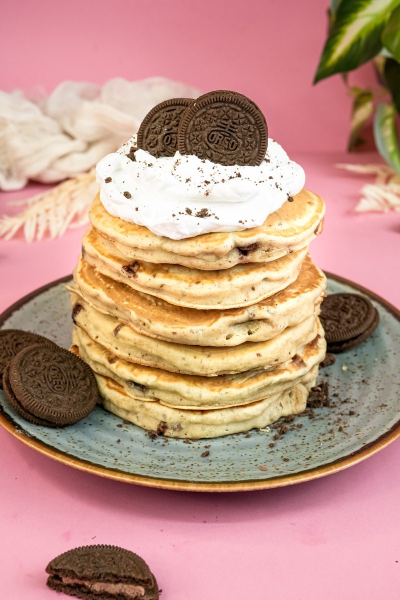 Homemade Oreo pancakes with whipped cream and cookie crumbs on blue plate