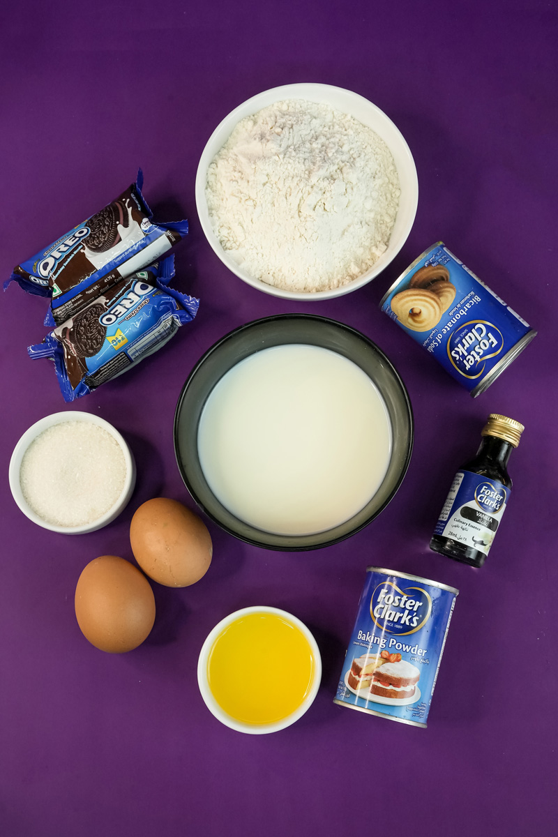Oreo pancake ingredients laid out: flour, milk, eggs, crushed Oreos, vanilla extract, baking powder