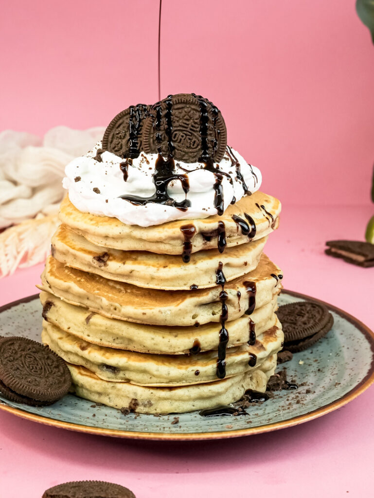 Oreo pancakes with chocolate syrup dripping and multiple cookie toppings