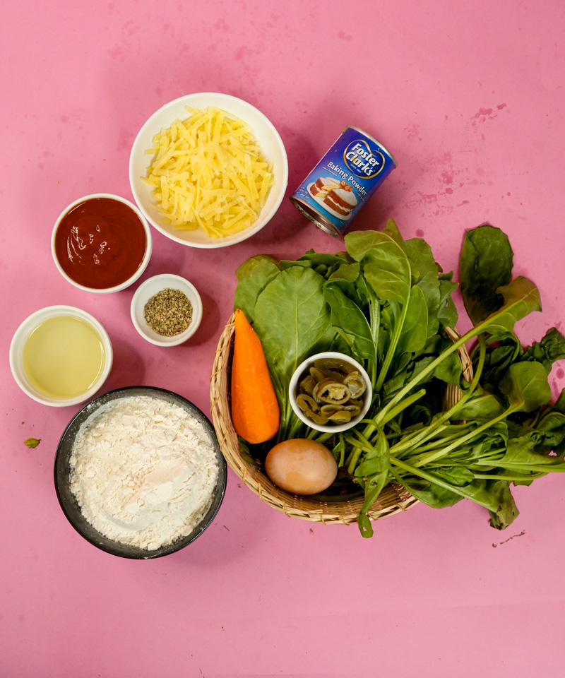 Pizza muffin ingredients laid out - flour, cheese, vegetables, sauce