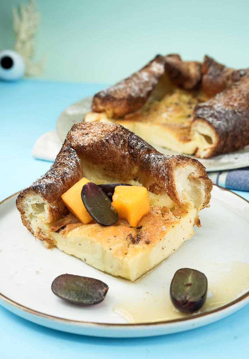 Plated German pancake slice topped with orange pieces and grapes