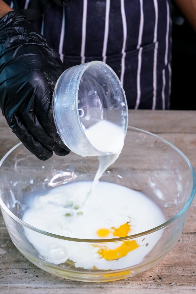 Pouring milk into bowl with egg for pancake batter