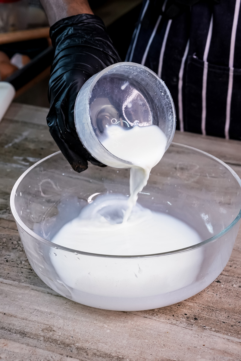 Pouring milk into glass bowl for whole wheat pancake batter preparation