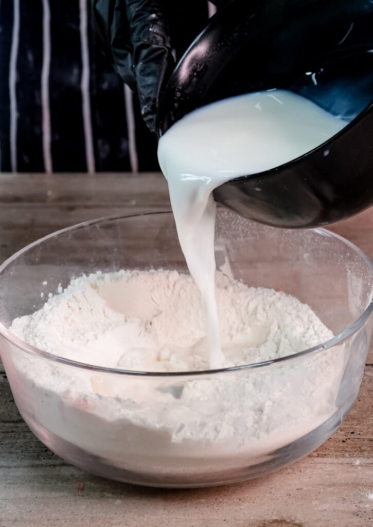 Pouring milk into gluten-free flour mixture in glass bowl