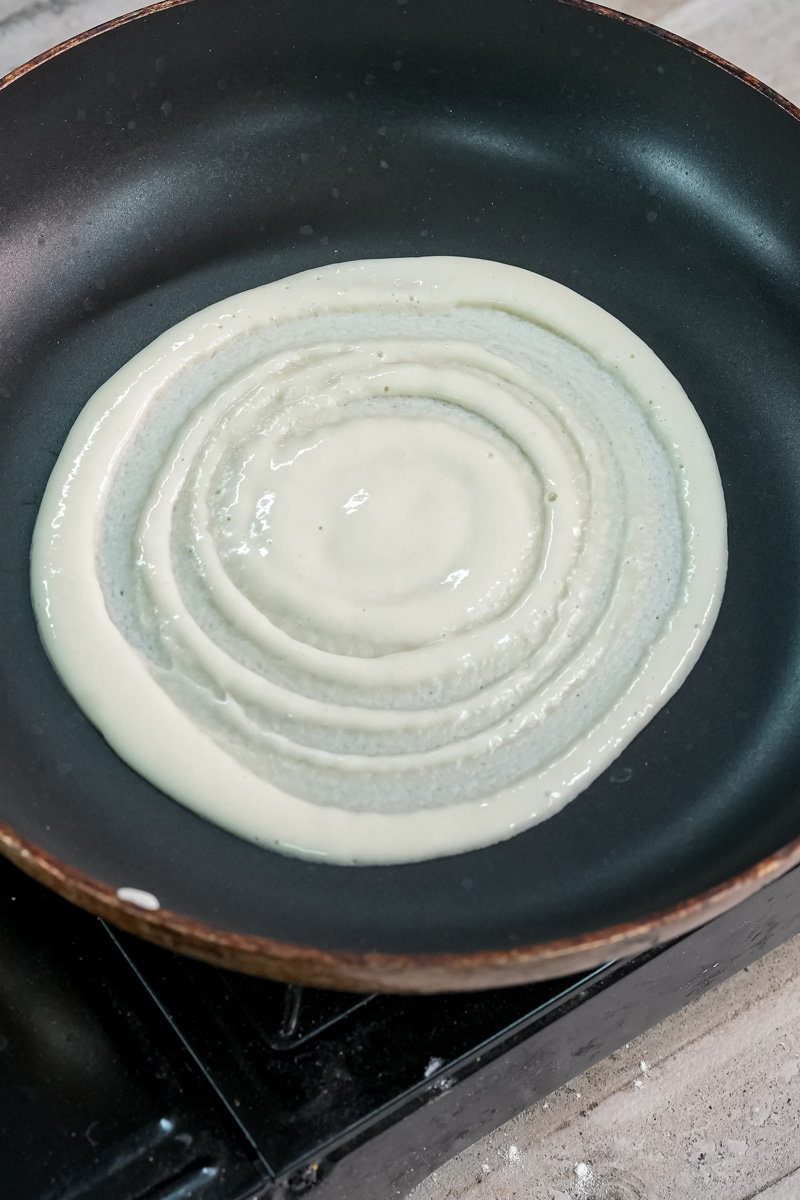 Pouring pancake batter into non-stick pan in spiral pattern