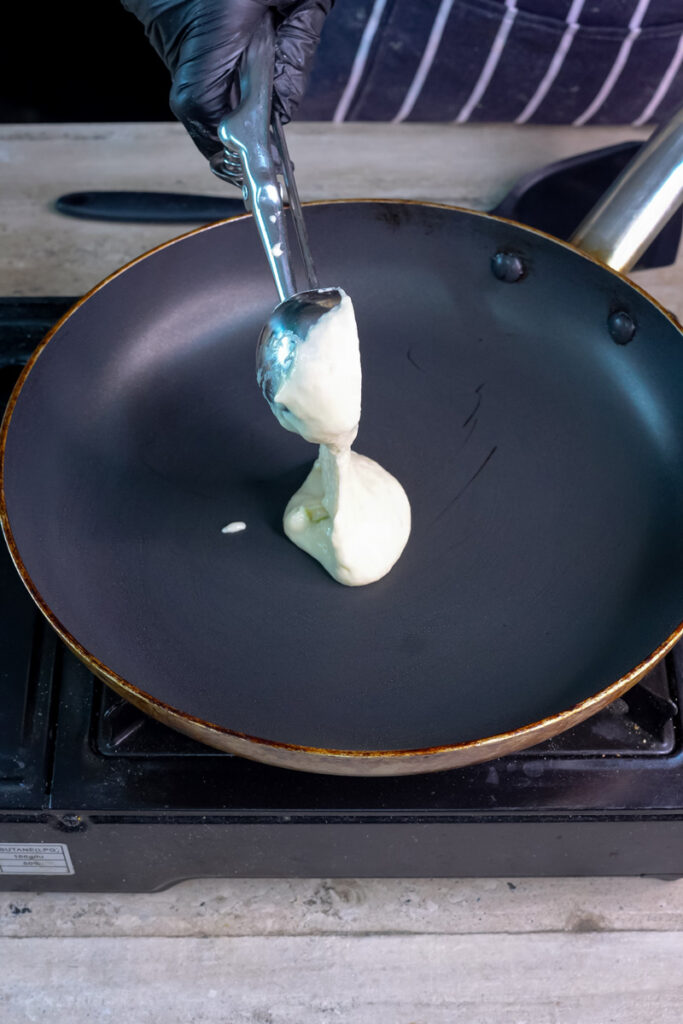 Pouring pancake batter into pan to make silver dollar pancakes