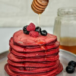 Honey drizzle over red velvet pancakes with fresh berries