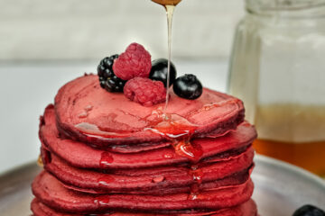 Honey drizzle over red velvet pancakes with fresh berries