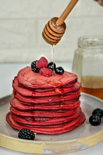 Honey drizzle over red velvet pancakes with fresh berries