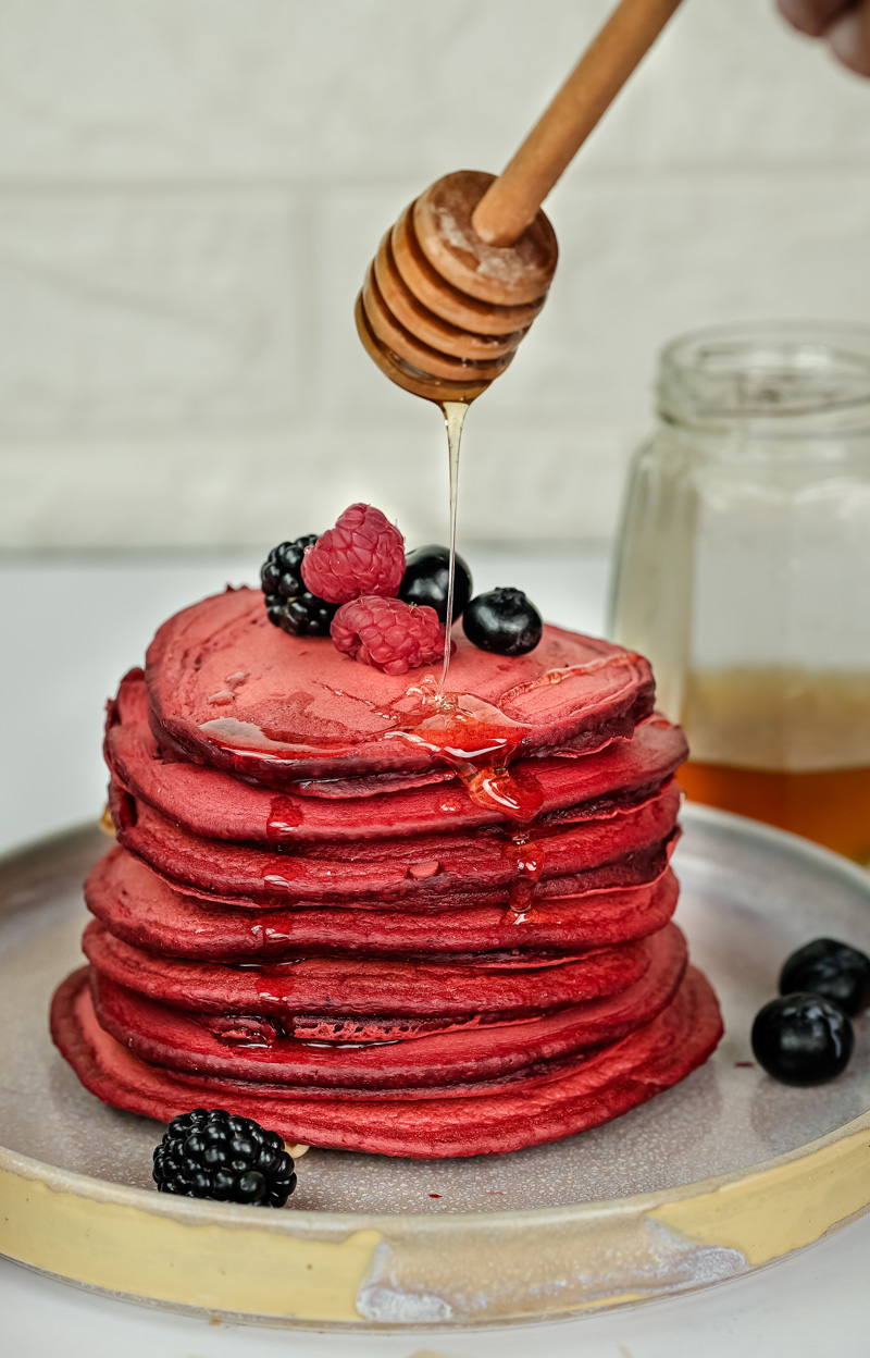 Honey drizzle over red velvet pancakes with fresh berries