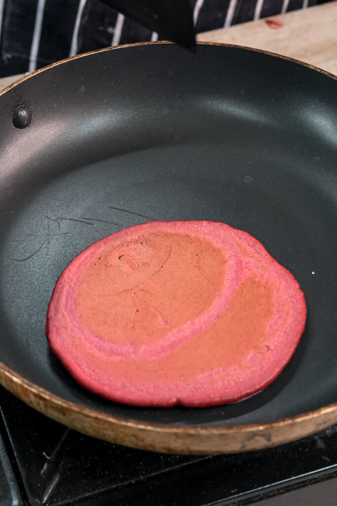 Red velvet pancake with bubbles forming while cooking