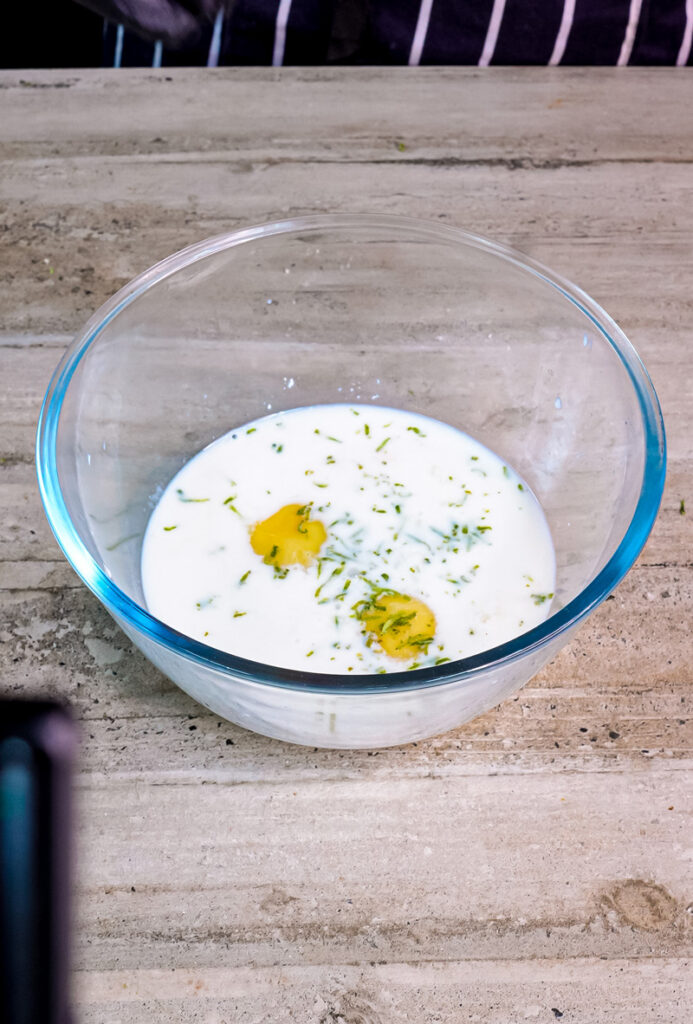 Ricotta cheese and eggs with lemon zest in glass bowl