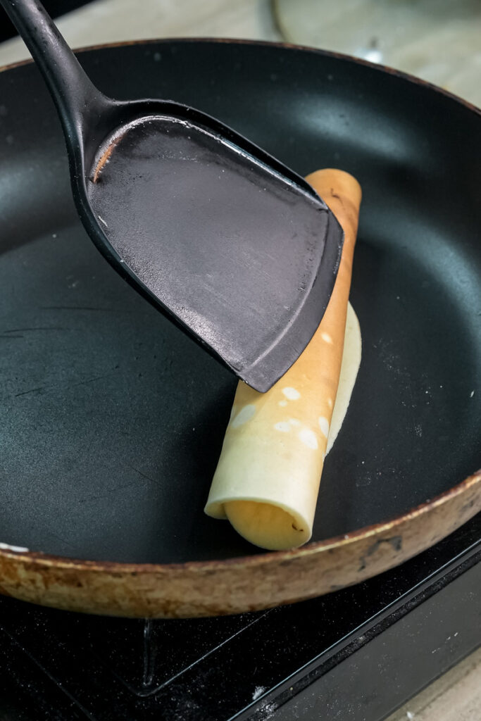 Rolling cooked pancake with spatula