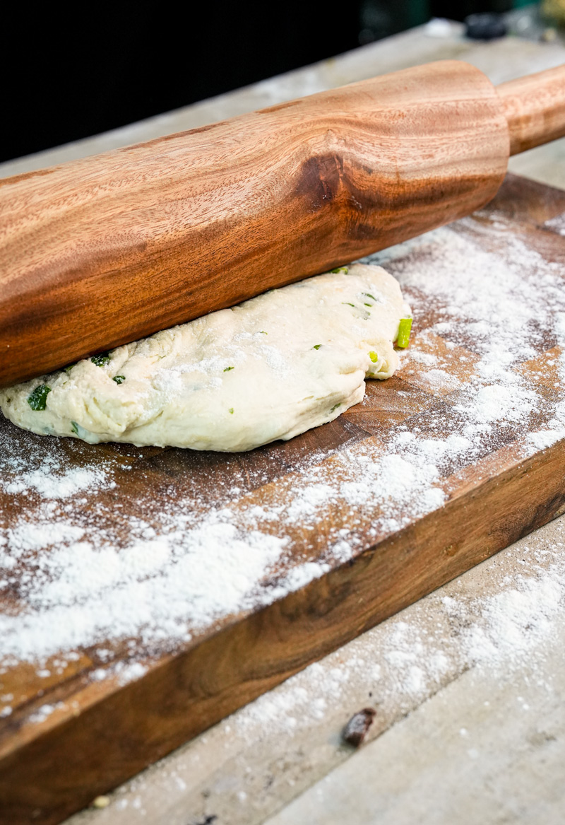 Rolling out Chinese scallion pancake dough with wooden rolling pin