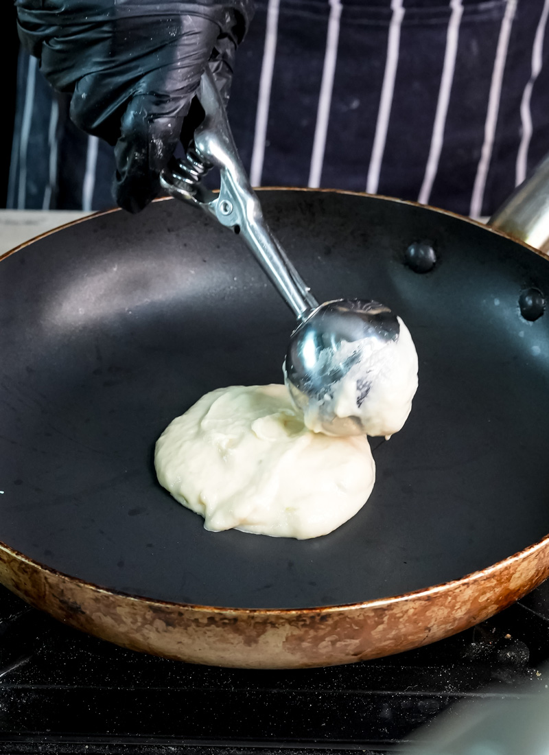 Scooping lemon ricotta pancake batter onto hot griddle pan