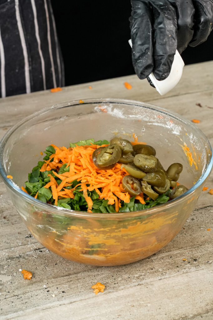 Sliced green olives being added to pizza muffin ingredients