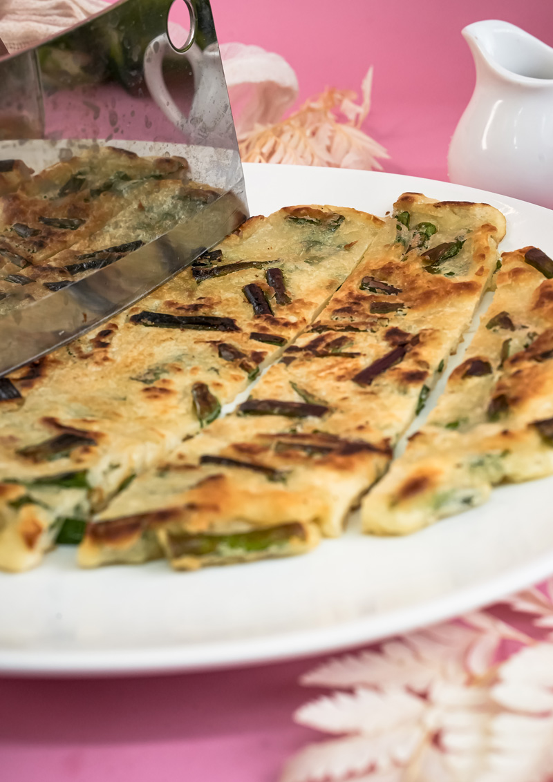 Slicing hot pajeon into serving pieces with scissors