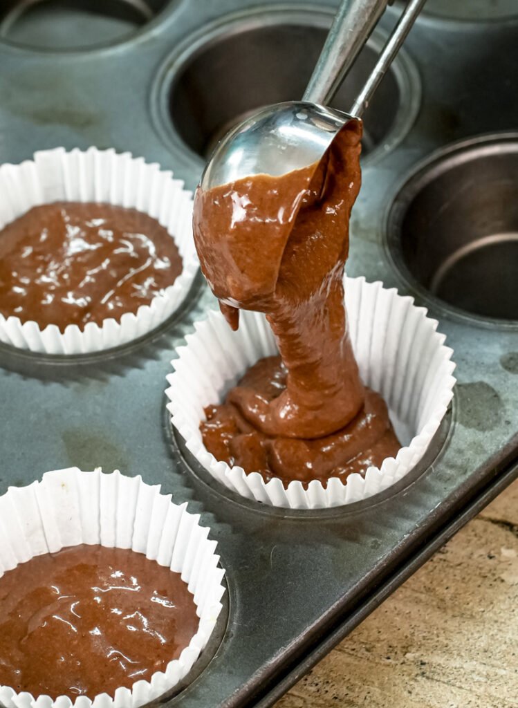 Spooning peanut butter banana muffin batter into cupcake liners