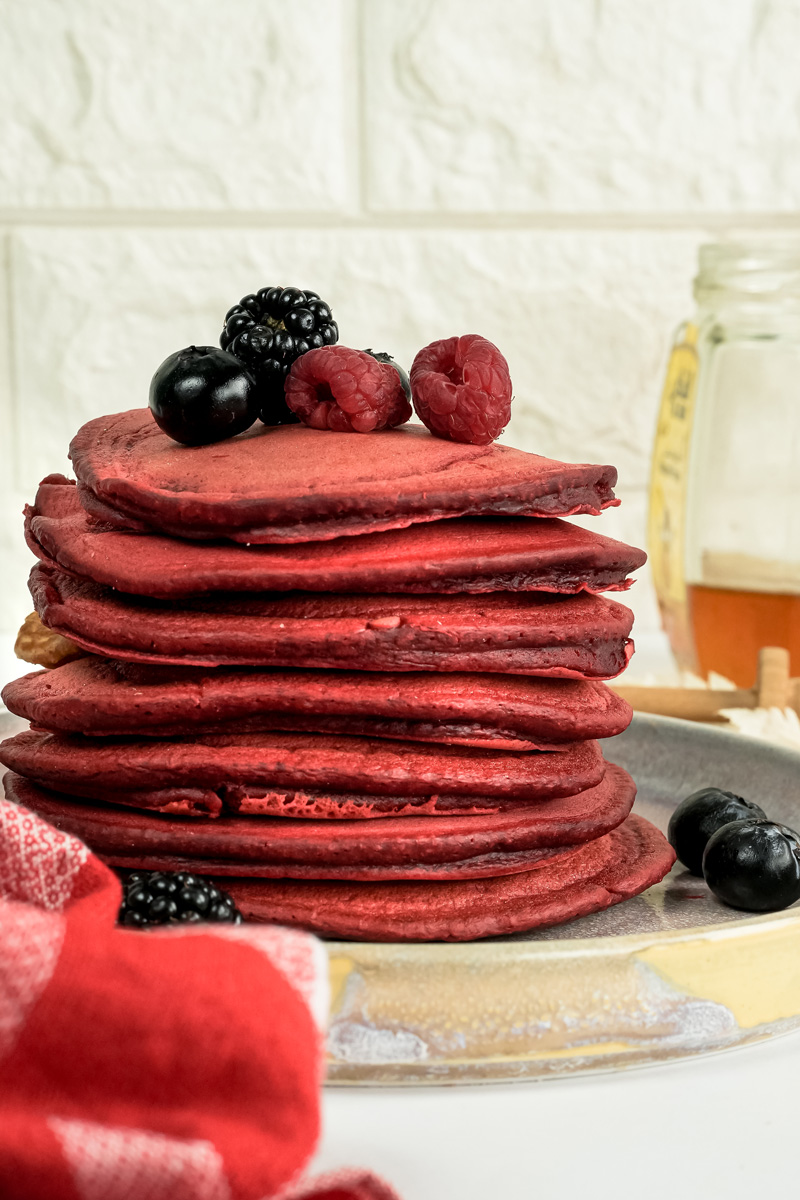 Stack of red velvet pancakes topped with fresh berries