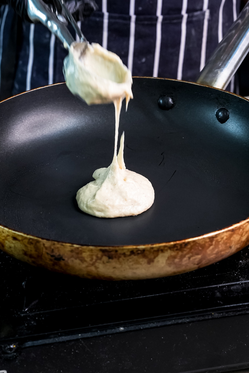 Ladling whole wheat pancake batter onto non-stick pan for cooking