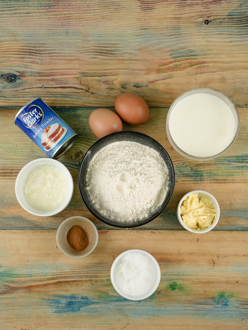 Whole wheat pancake ingredients on wooden board including flour, eggs, milk and baking powder