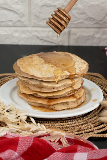 Whole wheat pancakes with honey drizzle on serving plate