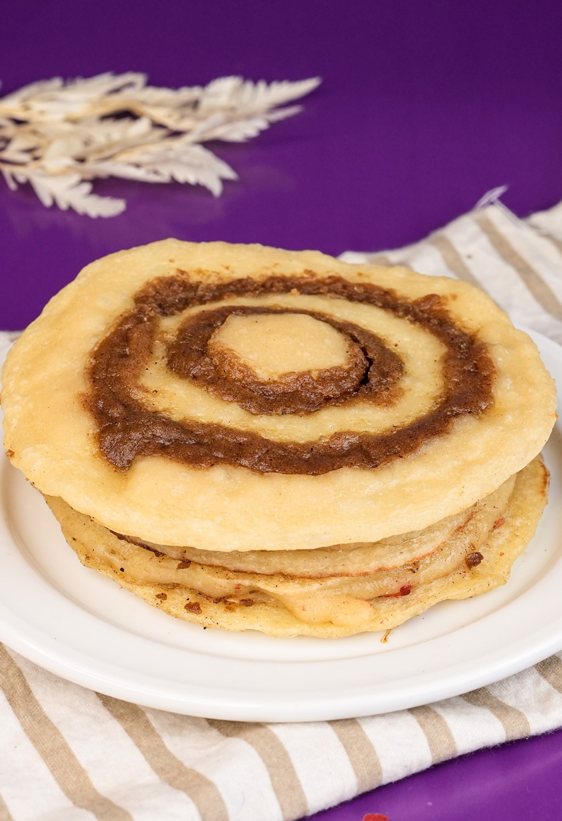 Finished cinnamon roll pancake with perfect spiral pattern on white plate