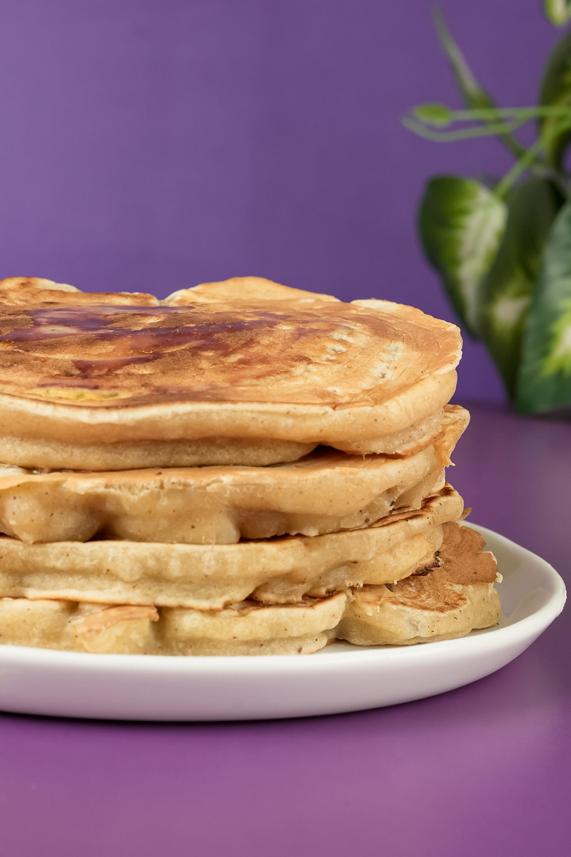 Stack of fluffy apple cinnamon pancakes on white plate