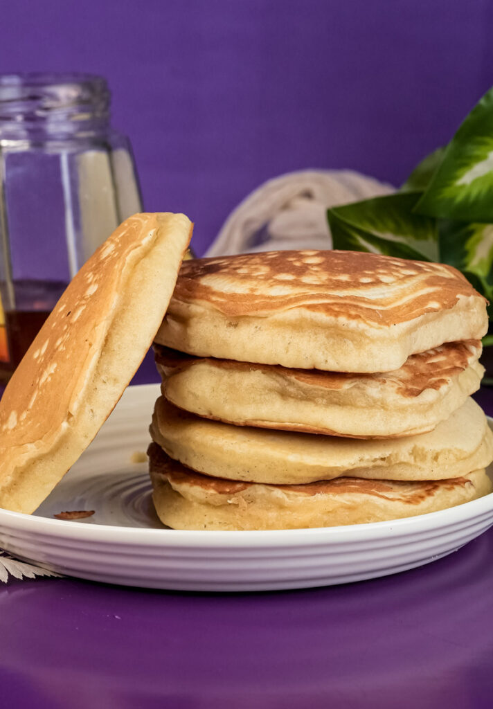 Stack of fluffy gluten-free pancakes on white plate