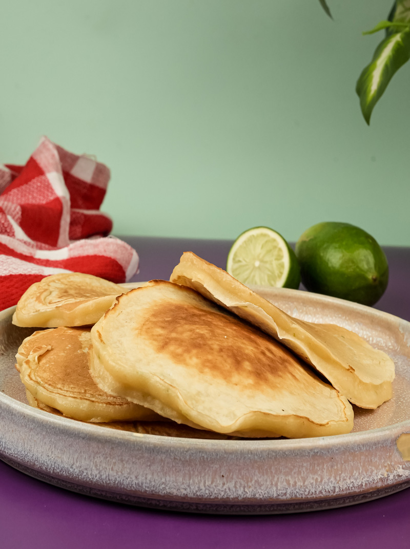 Stack of fluffy lemon ricotta pancakes with lime wedges