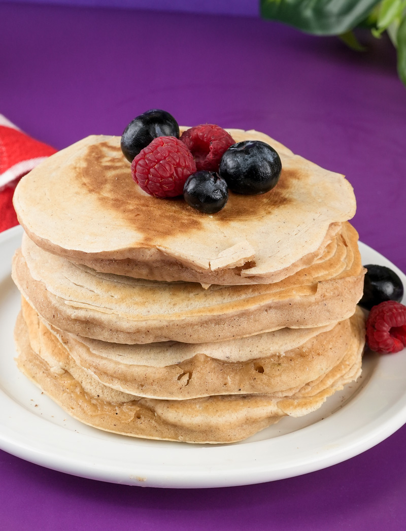 Stack of fluffy silver dollar pancakes topped with fresh blueberries and raspberries